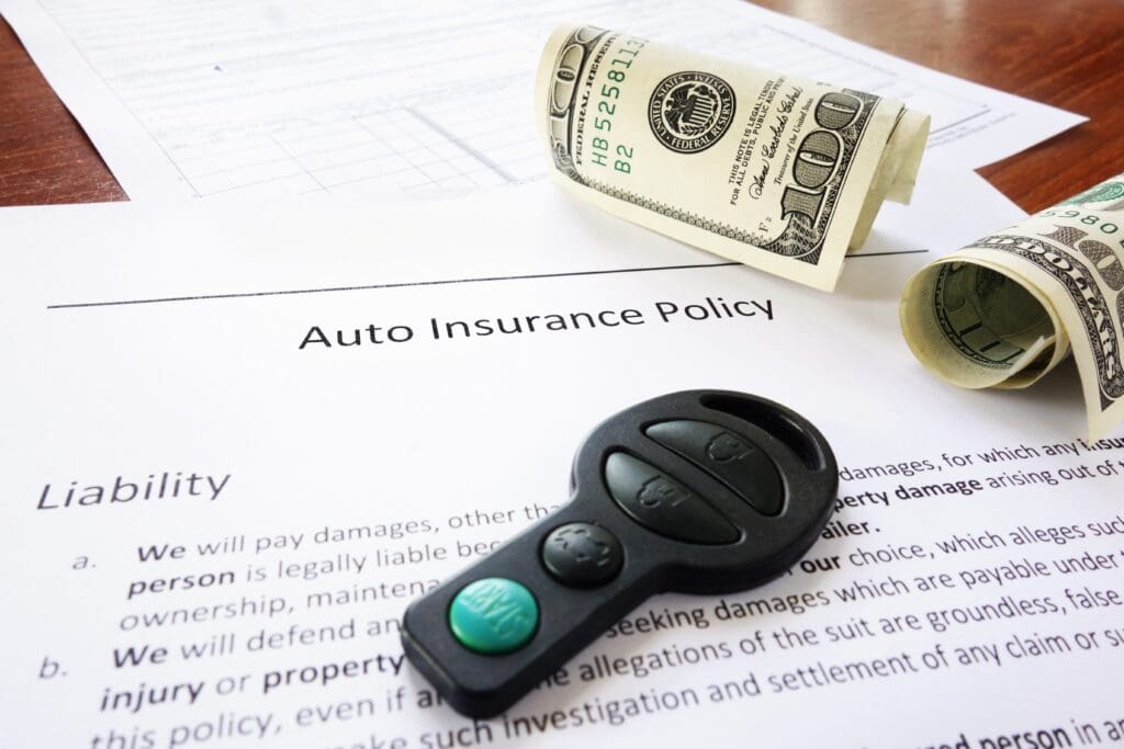 money and insurance policy on a table with a car key
