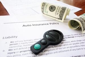 money and insurance policy on a table with a car key