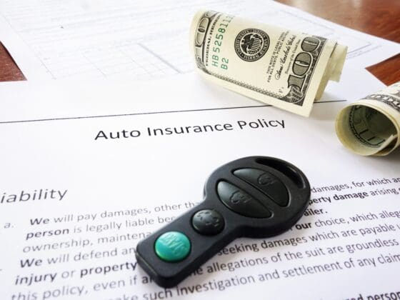 money and insurance policy on a table with a car key