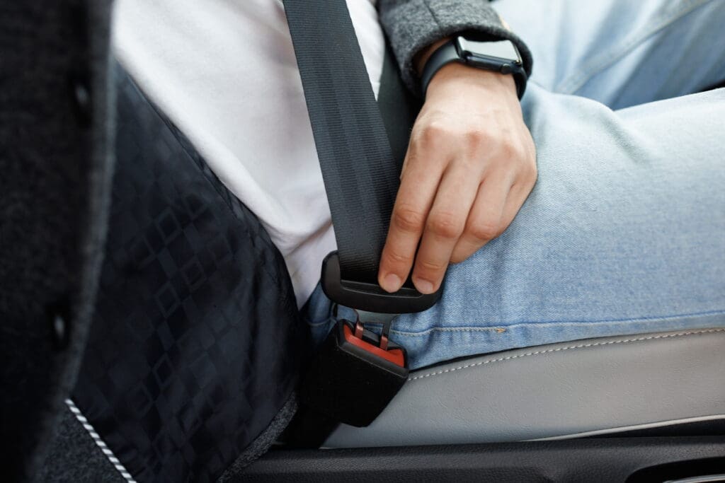 man buckling seatbelt in a car which can cause seat belt syndrome